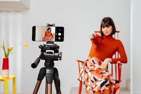 Woman uses the phone holder for her tripod to take a selfie.