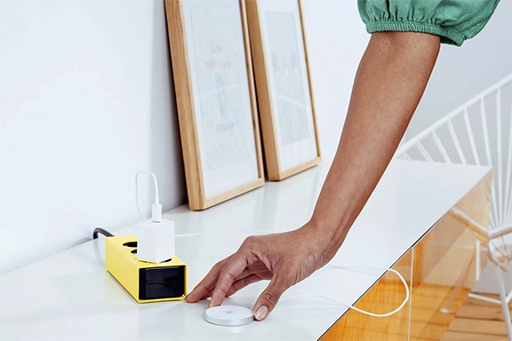 MagSafe charger is connected to a multiple-socket power strip and lies on a sideboard.