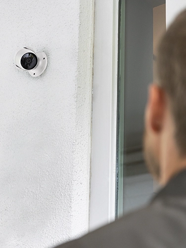 A man stands in front of a front door and is filmed by the Hama surveillance camera