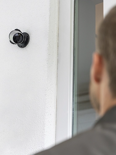 A man stands in front of a front door and is filmed by the Hama surveillance camera